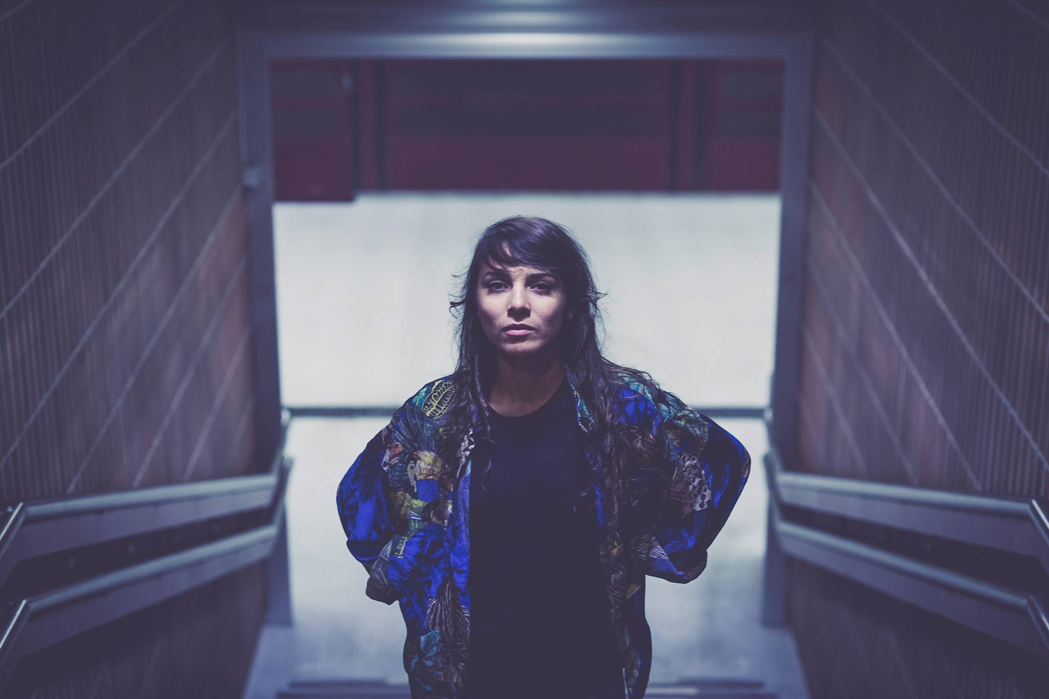 A photo of Safira, standing in a stairway, looking towards the camera.